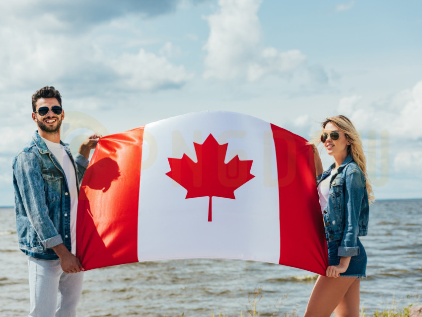 attractive woman and handsome man smiling and holding canadian flag