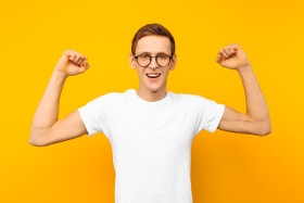 Man in Glasses, Dressed in a White T Shirt, the Man Who Won Shows a Gesture of Victory and Success, on a Yellow Background